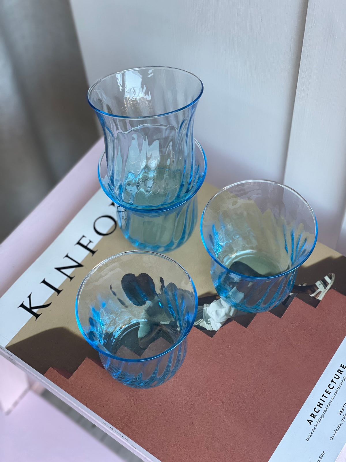 Lyseblå italienske vintage vandglas med swirl-mønster på et magasin