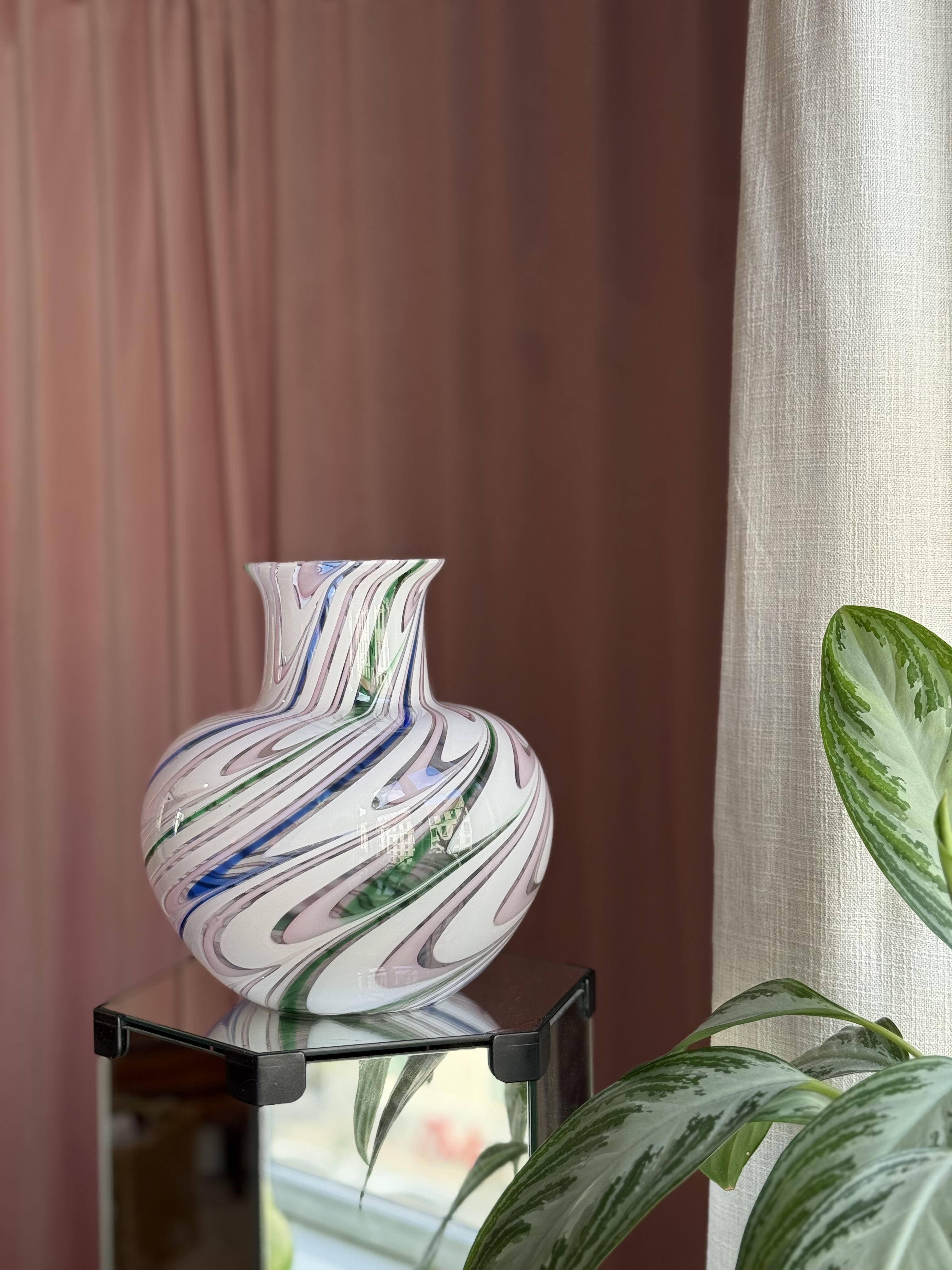 Hvid Murano vase med snoede tråde i lyserød, grøn og blå på et glasbord